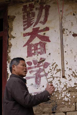 Xu Zhenguang knocks the "school bell" at the primary school of Siliu Village in Rongshui County, southwest China