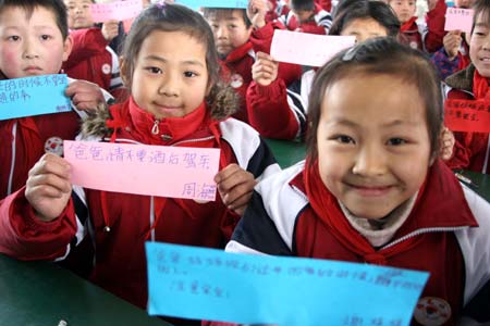 Children show the words written for their migrant-worker parents about the traffic safety on their way home at Guanzhen primary school in Hanshan County, east China's Anhui Province, Jan. 13, 2009. Traffic policemen in the county help children send messages to their parents who work in other cities to remind them of traffic safety before the Chinese traditional Spring Festival.[Cheng Qianjun/Xinhua] 