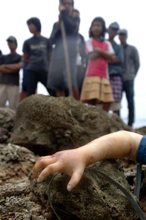 Local residents stand near the body of a baby who died in the ferry sinking accident near Pare-Pare port, Sulawesi Island, Indonesia, on Jan. 13, 2009. Rescuers found the first body of baby victims in this accident on Tuesday. 