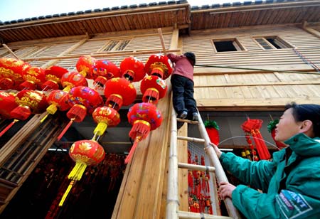 Two women decorate their shop with lanterns in Fuzhou, capital of east China's Fujian Province Jan. 13, 2009, as the traditional Chinese Lunar New Year approaches.[Xinhua]