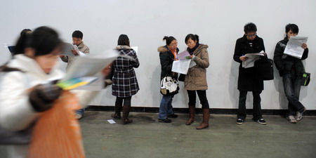 Jobseekers read leaflets of want ads at a job fair for college graduates at Hangzhou Peace International Convention and Exhibition Center in Hangzhou, east China's Zhejiang province January 13, 2009. [Xinhua]