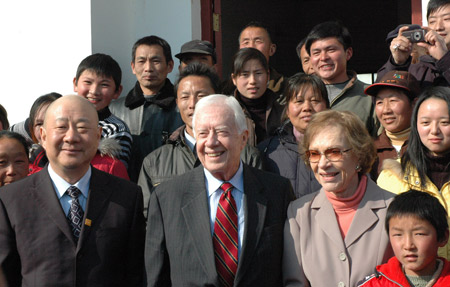  Former U.S. President Jimmy Carter (2nd L, front) and his wife (3rd L, front) pose in front of a local medical center at a village in Hong'an County, central China's Hubei Province, on Jan. 14, 2009. [Xinhua]