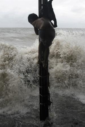 A boy clings to a pole while high tides strike a fish market in Jakarta Jan. 14, 2009. Flooding caused by unusually high tides were still happening in some part of Indonesia , a meteorology official said on Tuesday. [Xinhua/Reuters]