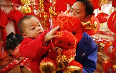 A child touches a doll cow bought by his father at a market in Guiyang, capital of southwest China's Guizhou Province, Jan. 13, 2009. People were busy in selecting decorations and goods to greet the Chinese traditional Spring Festival, which falls on Jan. 26 this year.[Xinhua]