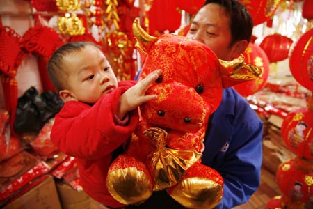 A child touches a doll cow bought by his father at a market in Guiyang, capital of southwest China's Guizhou Province, Jan. 13, 2009. People were busy in selecting decorations and goods to greet the Chinese traditional Spring Festival, which falls on Jan. 26 this year.[Xinhua]