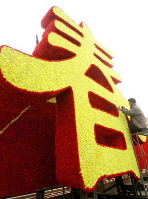 A worker arranges flowers-weaved Chinese character of 'chun' (meaning 'spring') on the Ganjiang Road in Suzhou, east China's Jiangsu Province, Jan. 14, 2009. As the Year of Ox in Chinese lunar calendar approaching, the city is permeated with a holiday atmosphere. The Chinese Year of Ox will start from Jan. 26, 2009. [Hang Xingwei/Xinhua] 