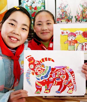 Two girls shows their handmade Taohuawu woodcut New Year paintings in Taowu Central Elementary School in Suzhou, east China&apos;s Jiangsu Province, Jan. 14, 2009. An activity with the theme of greeting the Chinese Year of Ox was held here during which pupils made Taohuawu New Year paintings and presented to their parents, friends and teachers. (Xinhua/Wang Jianzhong)