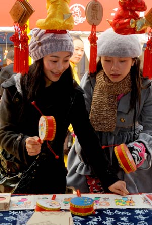 Girls choose their favourite lunar New Year paintings, a type of traditional Chinese decoration for the lunar New Year, during the 2009 Lunar New Year Paintings Festival held in Mianzhu, one of the worst-hit towns during the May 12 quake in southwestern Chinese province of Sichuan, Jan. 15, 2009. [Chen Xie/Xinhua]