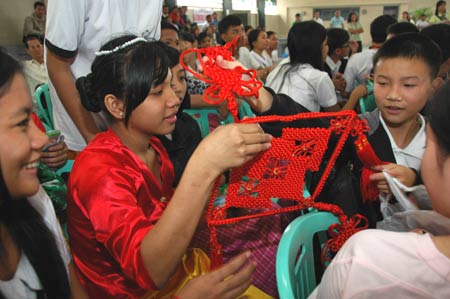 Philippine students receive a Chinese knot as a gift from their Chinese companions at the Raja Suliman Science And Technology High School in Manila, the Philippines, Jan. 15, 2009. Invited by Philippine President Gloria Macapagal-Arroyo, a group of 100 children who survived a devastating earthquake in China last May arrived in the Philippines on Sunday for a week-long trip.[Xinhua]