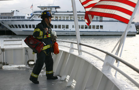 A firefighter waits on the deck of a rescue boat as it heads out to a U.S. Airways plane that crashed into the Hudson River in New York, January 15, 2009. [Xinhua/Reuters]