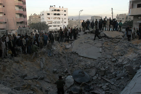  Palestinians gather around the crater caused by an Israeli strike, which hit the house of top Hamas official Said Siam's brother in Gaza City, Jan. 15, 2009. [Xinhua]