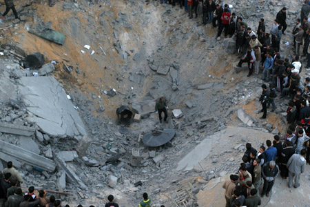 Palestinians gather around the crater caused by an Israeli strike, which hit the house of top Hamas official Said Siam's brother in Gaza City, Jan. 15, 2009. [Xinhua]