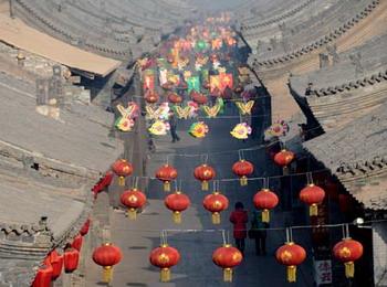 Local citizens walk along a street decorated with lanterns in Pingyao. 