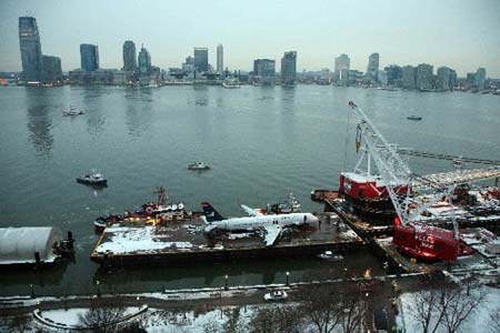 Emergency crew workers work to place the wreckage of the US Airways airplane that crashed in the Hudson River on a barge as it is hoisted out of the river in New York January 17, 2009.
