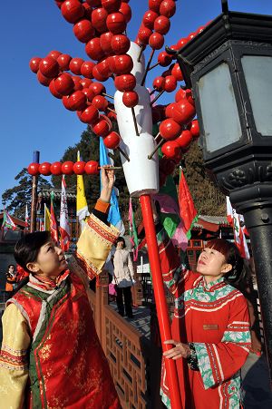 Workers in ancient Chinese dress decorate the street with mock Tanghulu, a Beijing&apos;s traditional snack made of sugarcoated haws and other fruit on a stick, for the royal temple fair in the Summer Palace in Beijing, Jan. 18, 2009.