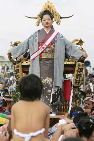 A 20-year-old girl stands on a portable shrine carried by people along the seashore during a purification ceremony at the Katase-Enoshima beach in Fujisawa of Kanagawa prefecture Jan. 18, 2009. The annual ceremony celebrates the coming-of-age for young people.