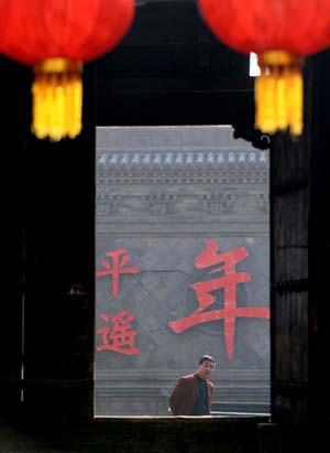 A man looks in through a door decorated with lanterns in Pingyao, north China's Shanxi Province, Jan. 17, 2009. The time-honoured Pingyao city listed among the UNESCO World Cultural Heritages prepares for the approaching Spring Festival with traditional celebrations. 