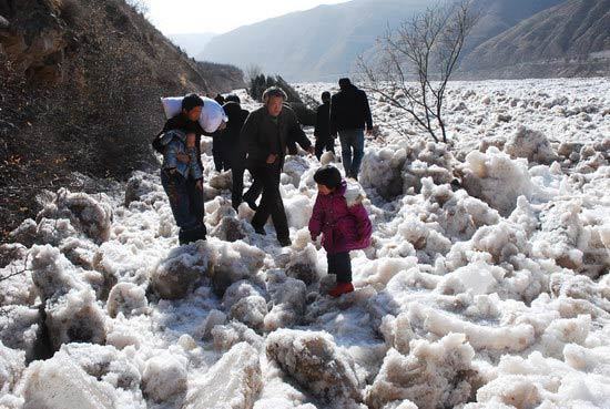 People walk on a road covered by the ice surge. 