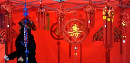 A staff member walks through works of Chinese knots during a fair of the intangible cultural heritage, in Changsha, capital of central China's Hunan Province, Jan. 17, 2009. 