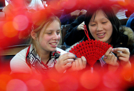 Two New Zealand students learn weaving a Chinese knot in Shandong Normal University in Jinan, capital of east China's Shandong Province, Jan. 19, 2009. A total of 18 students from New Zealand studying at the college learned Chinese folk custom ahead of the traditional Spring Festival, which falls on Jan. 26 this year. [Xinhua] 