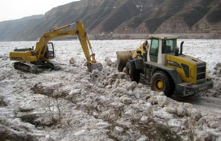 Bulldozers clear ice stacks off the road at the Hukou (Kettle Mouth) Cataract scenery spot in Jixian county, north China's Shanxi Province, Jan. 19, 2009. Some 6 million cubic meters of ice was piled up around Hukou Cataract on the Yellow River due to the warm weather, paralysing the tour traffic. 