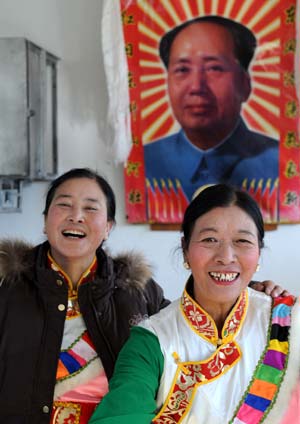 Two smiling women of the Tibetan ethnic group pose for a picture in front of the portrait of late Chinese leader Mao Zedong, in Lhasa, capital of southwest China&apos;s Tibet Autonomous Region, Jan. 19, 2009. 