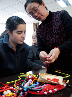 Hu Lihua (R), a folk artisan, shows the skill of weaving Chinese knots to a New Zealand student in Shandong Normal University in Jinan, capital of east China's Shandong Province, Jan. 19, 2009. 