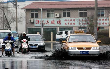 A taxi runs past the sludge in Baoshan District of Shanghai, east China, Jan. 19, 2009. A stack of river channel sludge collapsed here on Monday, leaving a bazaar and shops nearby affected. No casualties were reported by press time. [Liu Ying/Xinhua]