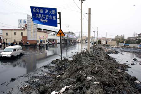 Photo taken on Jan. 19, 2009 shows the collapsed fence of the sludge field in Baoshan District of Shanghai, east China. A stack of river channel sludge collapsed here on Monday, leaving a bazaar and shops nearby affected. No casualties were reported by press time. [Liu Ying/Xinhua]