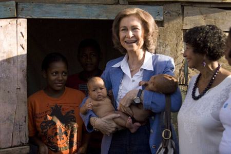 Spain's Queen Sofia (C) holds two babies during a short visit in a volatile neighborhood in Santo Domingo January 20, 2009.