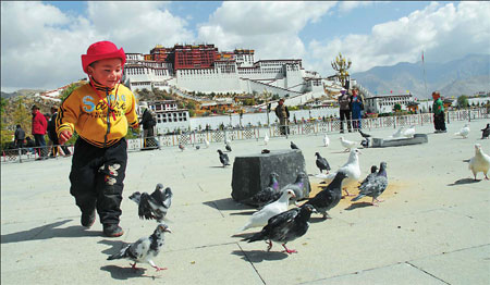 A child chases pigeons in front of the Potala Palace in Lhasa, capital of the Tibet autonomous region, in this photo taken last May. Tremendous changes have taken place since the emancipation of serfs in the region 50 years ago. [China Daily]