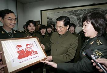 Hu Xuzhe (R), an instructor of local communication station of China's People's Liberation Army (PLA) General Staff Headquarters, present a paper cut work to Chinese President Hu Jintao (C, front), who is also General Secretary of the Communist Party of China (CPC) Central Committee and chairman of the Central Military Commission (CMC), in Beijing, capital of China, Jan. 21, 2009. [Ma Zhancheng/Xinhua]