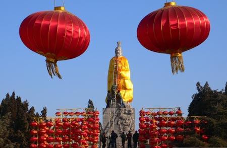 Workers put on a yellow robe for the statue of Yellow Emperor, a legendary Chinese sovereign and cultural hero and considered to be the ancestor of all Han Chinese in Chinese mythology, for the preparation of the temple fair in Hanyuan Forest of Stone Tablets in Kaifeng, central China's Henan Province, Jan. 21, 2009. [Li Junsheng/Xinhua]