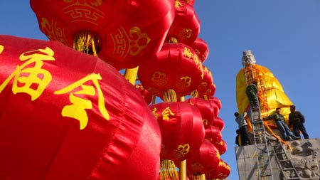 Workers put on a yellow robe for the statue of Yellow Emperor, a legendary Chinese sovereign and cultural hero and considered to be the ancestor of all Han Chinese in Chinese mythology, for the preparation of the temple fair in Hanyuan Forest of Stone Tablets in Kaifeng, central China's Henan Province, Jan. 21, 2009. [Li Junsheng/Xinhua] 