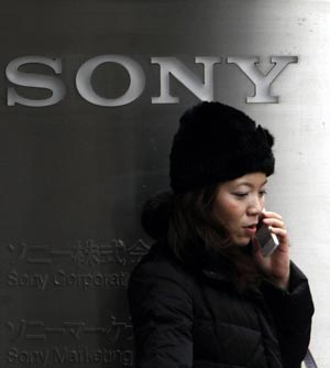 A woman stands by a signboard of Sony Corp at its branch building in Tokyo January 21, 2009. Sony Corp is preparing to announce on Wednesday or Thursday details of its December restructuring plan, including where job cuts will fall, the Financial Times reported.