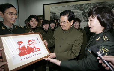 Hu Xuzhe (R), an instructor of local communication station of China's People's Liberation Army (PLA) General Staff Headquarters, present a paper cut work to Chinese President Hu Jintao (C, front), who is also General Secretary of the Communist Party of China (CPC) Central Committee and chairman of the Central Military Commission (CMC), in Beijing, capital of China, Jan. 21, 2009.