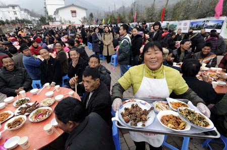 A woman serves with big smile on her face during a banquet to celebrate moving into new house in Dongjiaxinyuanzi town of Dujiangyan City, southwest China's Sichuan Province, Jan. 22, 2009. As their homestead was destroyed in the earthquake in May 2008, about 400 families in Dongjiaxinyuanzi town moved to new houses on Jan. 22. 