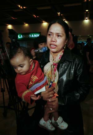 A woman evacuated from Gaza with her child speaks to the media upon their arrival in Manila, capital of the Philippines, Jan. 21, 2009. A total of 34 Gaza evacuees, including two Palestinian nationals, arrived in Manila late Wednesday night. This was the second batch of Filipino families, among 108 Filipino nationals residing in Palestinian terrority, who were moved out of Gaza amid escalated clashes under the Philippine government's evacuation plan.