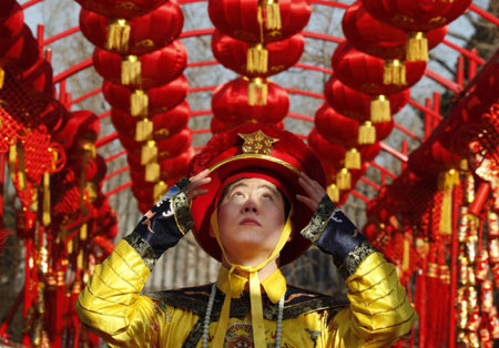 An actor who is dressed as a Qing Dynasty emperor adjusts his hat under red lantern decorations during a performance in Beijing January 23, 2009. The performance adapting the ancient ceremony of the Qing dynasty emperors to pray for good fortune will be held daily during the upcoming Chinese Lunar New Year celebrations in Beijing's Temple of Heaven.[Photo: Xinhua]