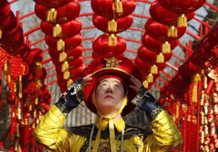 An actor who is dressed as a Qing Dynasty emperor adjusts his hat under red lantern decorations during a performance in Beijing January 23, 2009.