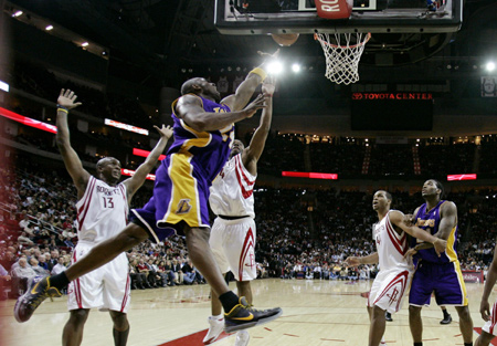 Los Angeles Lakers guard Kobe Bryant shoots a layup from under the basket against Houston Rockets guards Von Wafer (L) and Carl Landry (3rd L) during their NBA basketball game in Houston Jan. 13, 2009. 