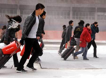 Passengers walk forward against chill and gale to railway station in Shanghai, east China, Jan. 23, 2009. [Photo: Xinhua]