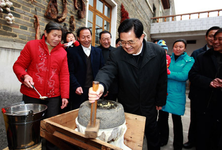 Chinese President Hu Jintao grinds soybean to make bean curd as he visits a farmer named Wu Jianzhong and his family in a village of Xiaping Township, east China's Jiangxi Province, Jan. 25, 2009, ahead of the Chinese Lunar New Year, China's most important holiday for family gatherings. 