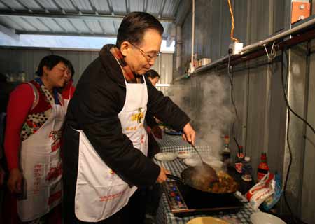 Chinese Premier Wen Jiabao (R) cooks at a kitchen shared by several families at the prefabs in Yingxiu Township of Wenchuan County, southwest China's Sichuan Province, Jan. 25, 2009. Wen Jiabao came to the quake-hit counties of Beichuan, Deyang and Wenchuan in Sichuan Province on Jan. 24 and 25, celebrating the Spring Festival with local residents.