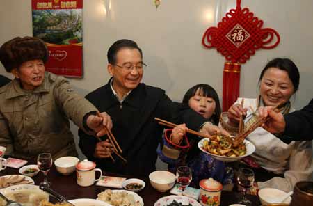 Chinese Premier Wen Jiabao (2nd L) shares the twice-cooked pork slices he cooked with family members of local resident Wu Zhiyuan, in Yingxiu Township of Wenchuan County, southwest China's Sichuan Province, Jan. 25, 2009. Wen Jiabao came to the quake-hit counties of Beichuan, Deyang and Wenchuan in Sichuan Province on Jan. 24 and 25, celebrating the Spring Festival with local residents.