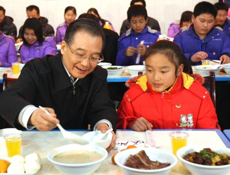 Chinese Premier Wen Jiabao (L) ladles porridge for Zhu Ke, a school girl, at the cafeteria of Beichuan Middle School in Beichuan County, southwest China's Sichuan Province, Jan. 24, 2009. Wen Jiabao came to the quake-hit counties of Beichuan, Deyang and Wenchuan in Sichuan Province on Jan. 24 and 25, celebrating the Spring Festival with local residents. 