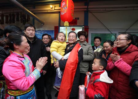 Chinese Premier Wen Jiabao (C) holds a girl in arms during his visit to the residents in Yingxiu Township of Wenchuan County, southwest China's Sichuan Province, Jan. 25, 2009. Wen Jiabao came to the quake-hit counties of Beichuan, Deyang and Wenchuan in Sichuan Province on Jan. 24 and 25, celebrating the Spring Festival with local residents. 