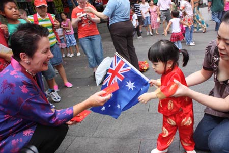 Sydney Mayor Clover Moore (L) presents gifts to a kid in Chinese Street to share the happiness of Chinese Lunar New Year in Sydney, Australia, Jan. 26, 2009.