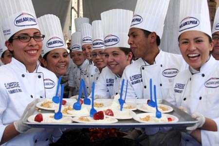 Chefs display pieces of a giant cheesecake that broke Guinness World Record for the biggest cheesecake of the world in Mexico City, capital of Mexico, Jan. 25, 2009. The cheese cake, with 2.5 meters in diameter, 55 centimeters in height and 2 tons in weight, was made by 55 chefs and 5 student chefs and cost 800 kilograms of cheese.