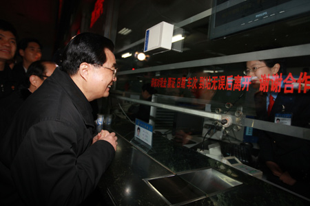 Chinese President Hu Jintao (Front) talks with a clerk to check whether travelers have difficulties in buying tickets at the Nanchang Railway Station in Nanchang, capital of east China's Jiangxi Province, Jan. 26, 2009. [Xinhua] 